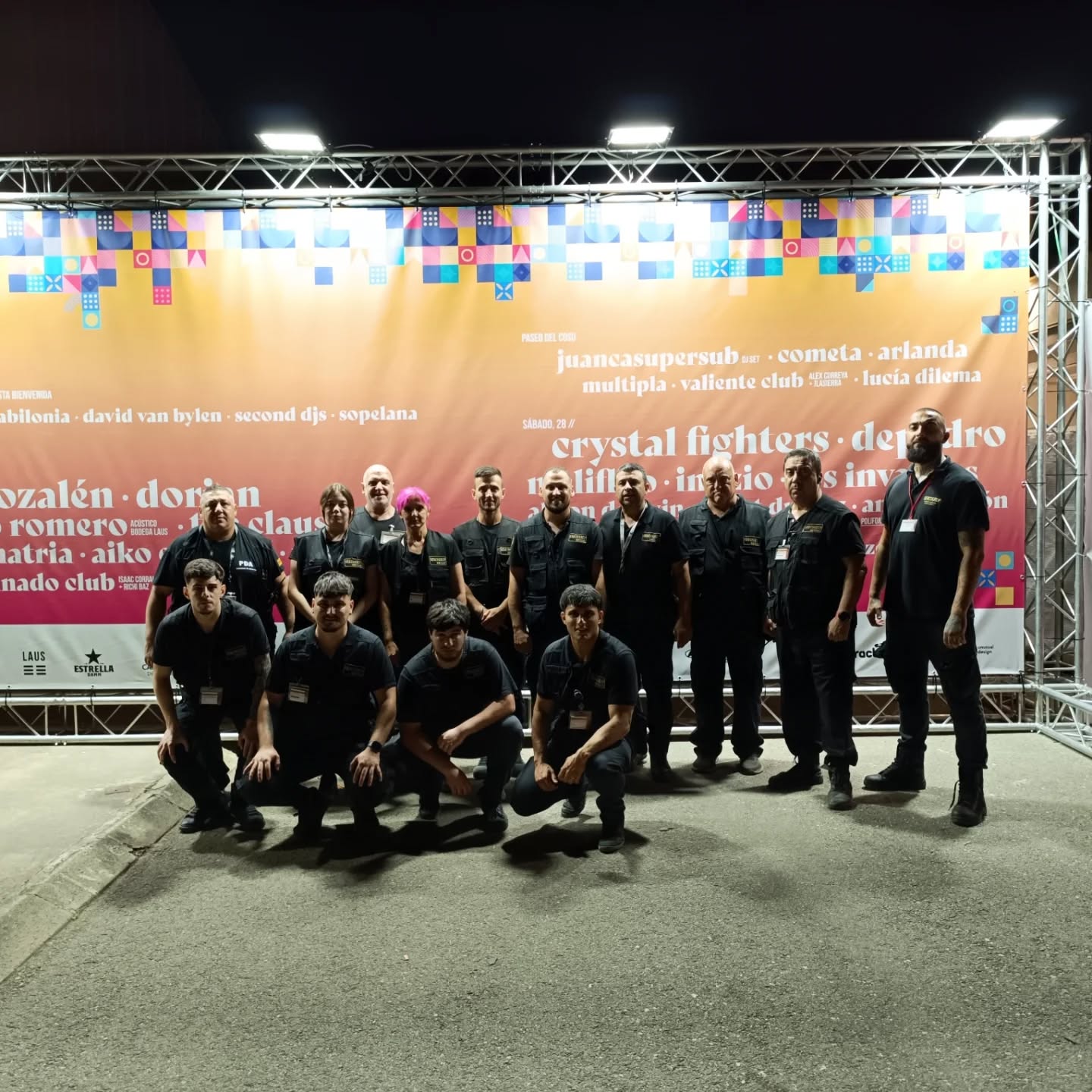 Equipo de seguridad en evento con banner colorido